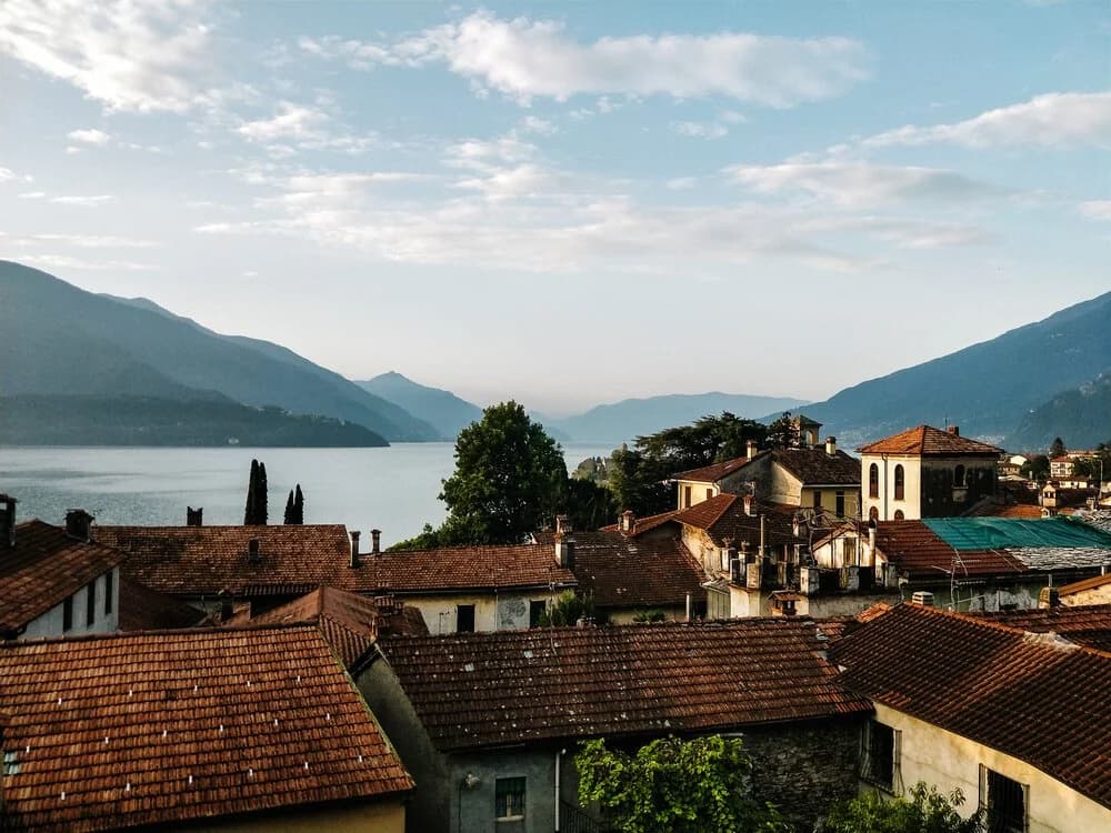 Terracotta rooftops beside Lake Como, with mountains rising across the water.