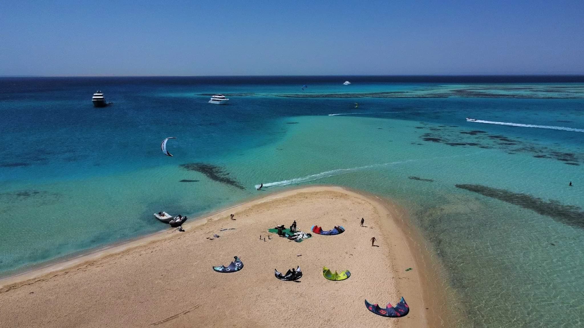 An aerial view of kites laid out on a sandbar in Egypt, with riders and boats in the surrounding water.