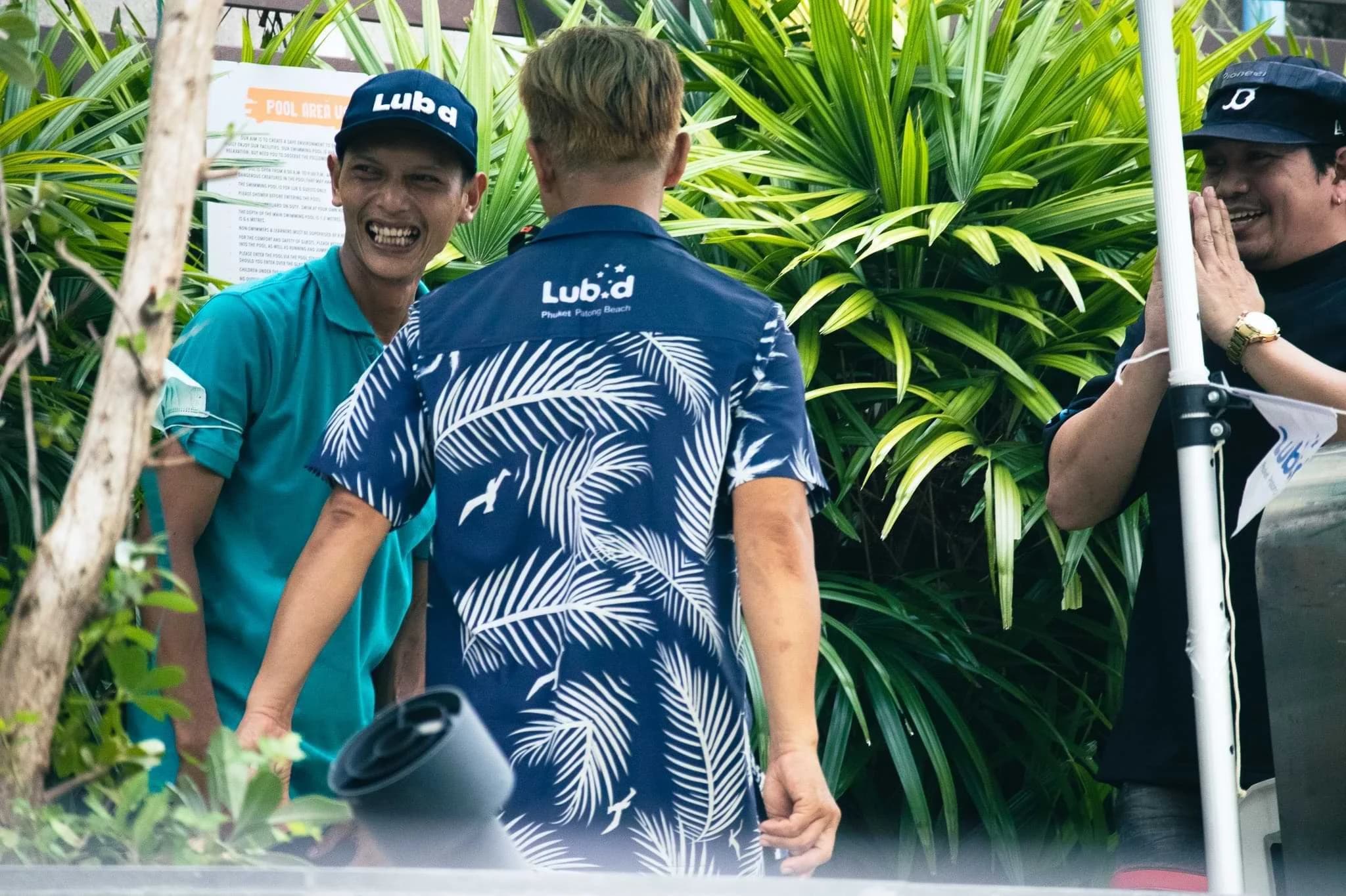 Three people chatting and smiling beside tropical plants at Lub d Patong, two wearing Lub d uniforms.