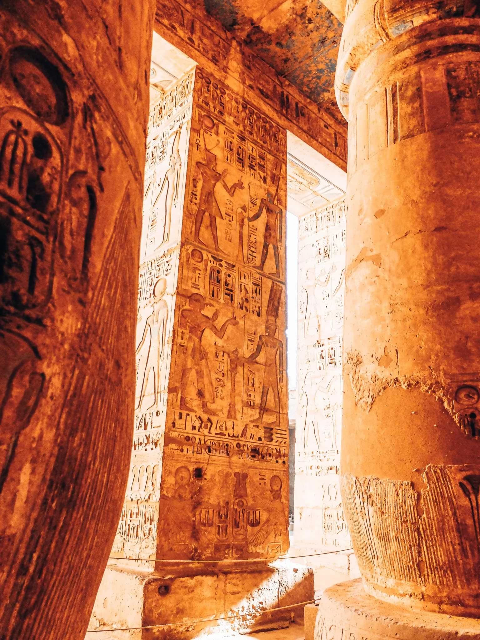 Sunlight falling across carved columns and walls at Medinet Habu temple.