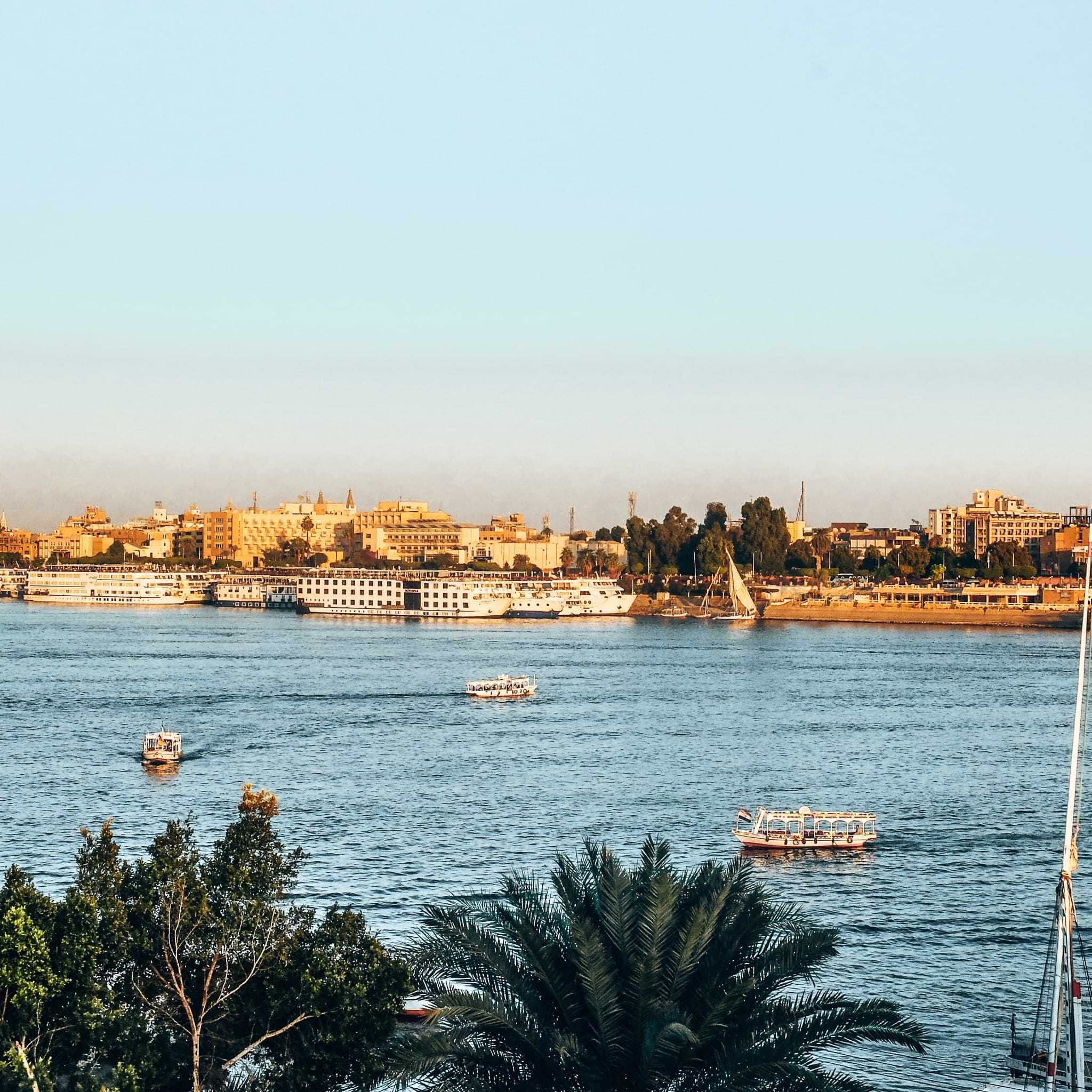 Boats crossing the Nile, with buildings along Luxor’s opposite bank.