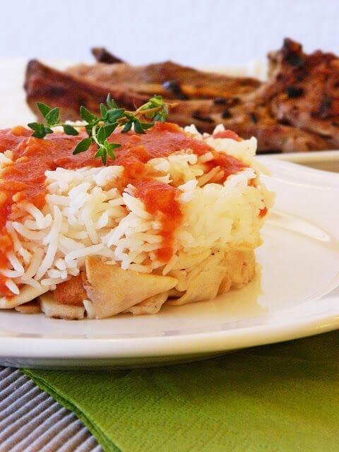 Fattah with rice and tomato sauce, served with meat on a white plate.