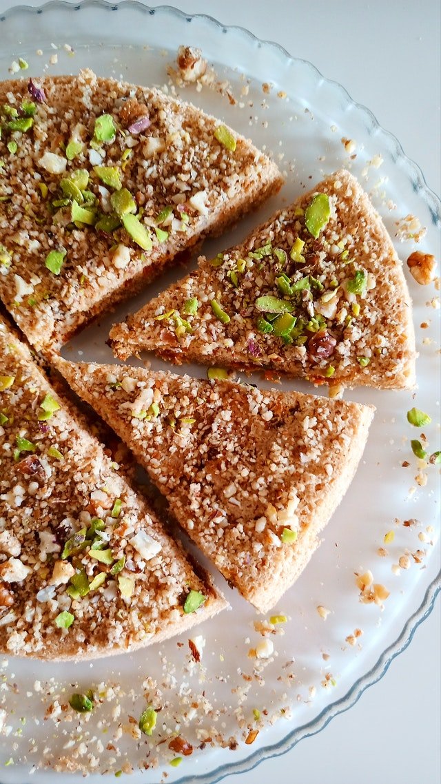 Slices of cake topped with chopped nuts on a glass plate.